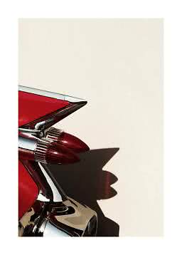 Close-up of a red vintage car tail fin with chrome and double tail lights against a light wall