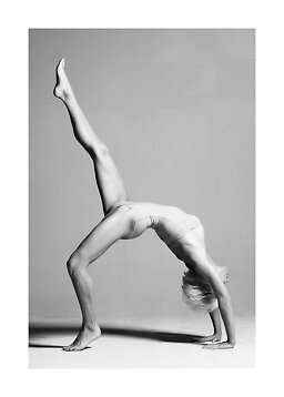 Woman in a light bodysuit doing a backbend with one leg raised in a black-and-white studio