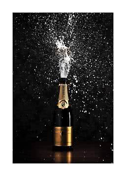 Champagneflaske med springende prop og skummende sprøjt mod sort baggrund