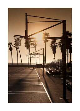 Beachside basketball courts at sunset with palm trees and empty bleachers