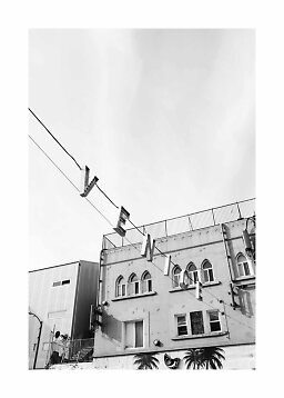 Black-and-white photo of a building with arched windows and hanging letters above the street