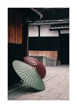 Twee traditionele papieren parasols staan bij een houten huis aan een rustige straat.