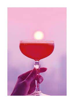 Hand hält Coupéglas mit rotem Cocktail vor rosa Hintergrund mit sanftem Sonnenschein