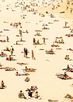 Travl sandstrand med mange solbadende og små grupper spredt ud i solen