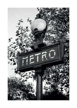 Schwarz-weißes Metro-Schild an einem Pfosten mit Lampe und Bäumen im Hintergrund