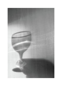 Stielglas mit Wasser und weichen Schatten auf heller Holzoberfläche
