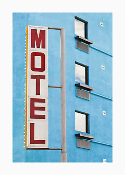 Vertikalt MOTEL-skilt på blå bygning med vinduer