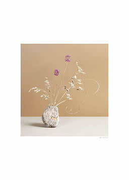 Minimalist still life with dried grasses and purple flowers in a rough stone-like vase.
