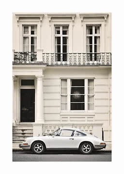 White classic sports car parked in front of a cream townhouse with balcony and tall windows