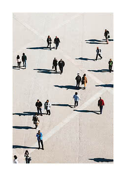 Overhead view of people walking across a large pale plaza with long shadows