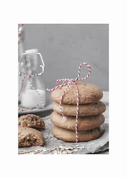 Pila di biscotti d’avena legati con spago rosso e bianco, con bottiglia di latte sullo sfondo