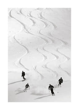 Vier skiërs dalen af op een besneeuwde helling met brede bochten in poedersneeuw.