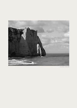Black-and-white photo of a coastal cliff with a natural arch under a cloudy sky