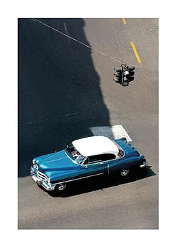 Overhead view of a blue vintage car with white roof on a street near a hanging traffic light