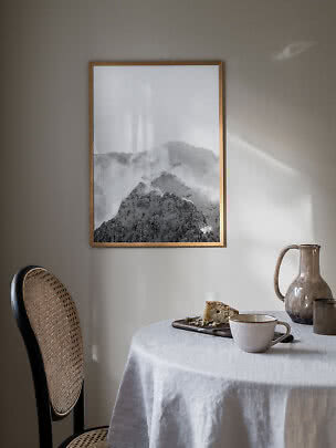 Gerahmter Schwarz-Weiß-Bergdruck an der Wand über Esstisch mit Tasse, Krug und Kuchen