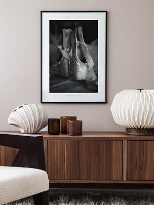Affiche encadrée en noir et blanc de chaussons de ballet au-dessus d'un buffet en bois