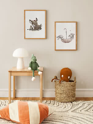 Children’s room with two framed animal prints, small table with lamp, and basket with plush toy