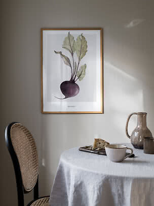 Ingelijste poster met bietillustratie boven een tafel met kopje, kan en cake.