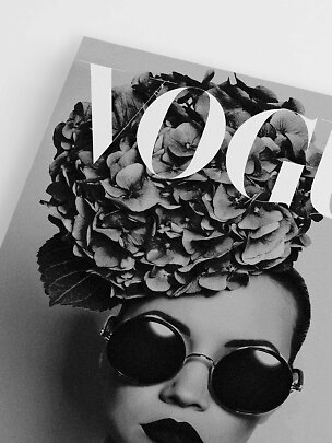 Black-and-white Vogue magazine cover with woman in round sunglasses and flowers on her head