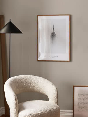 Stuehjørne med bouclé-lænestol, sort gulvlampe og indrammet Empire State Building-plakat på væggen