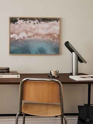 Indrammet strandfoto over skrivebord med stol, lampe, bøger og kop