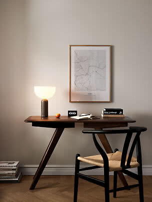 Dunkler Holzschreibtisch mit leuchtender Tischlampe, Stuhl und gerahmter London-Karte an der Wand