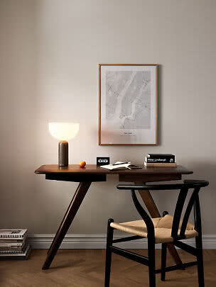 Dark wood desk with black chair, lit table lamp, and framed New York poster on the wall