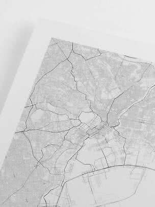 Primer plano de un póster de mapa urbano en blanco y negro con finas líneas de calles sobre fondo blanco