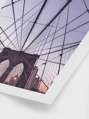 Fotografi af Brooklyn Bridge nedefra med kabler mod himlen i rosa aftenslys