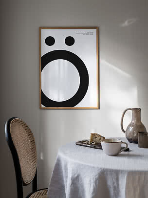 Poster tipografico incorniciato con grande Ö nera su sfondo bianco sopra una tavola apparecchiata