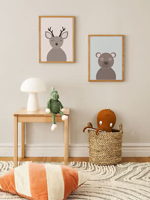 Kinderkamer met twee ingelijste dierenposters, lamp op houten tafel en gevlochten mand met octopusknuffel