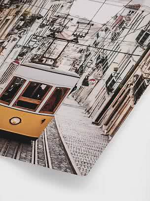 Yellow tram on a steep cobblestone street between narrow buildings and overhead wires