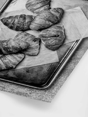 Diversi croissant su carta da forno su una teglia di metallo