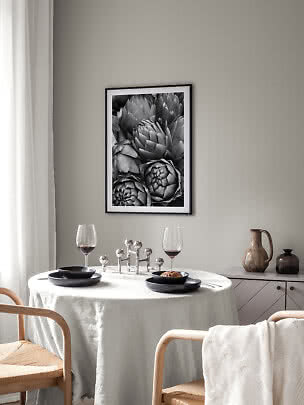 Affiche noir et blanc d’artichauts dans un cadre noir au-dessus d’une table dressée