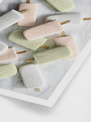 Pastellfarbene Eis am Stiel auf einer hellen Marmorplatte arrangiert