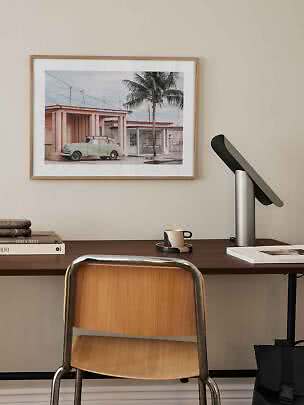 Framed photo print above desk with vintage car, palm tree and pastel houses