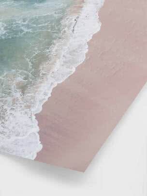 Luftfoto af bølger, der skyller ind over en lyserød sandstrand på et print