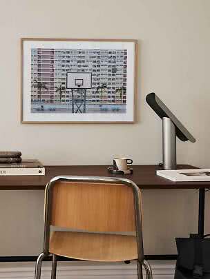 Framed photo print of a basketball hoop in front of apartment blocks above a desk