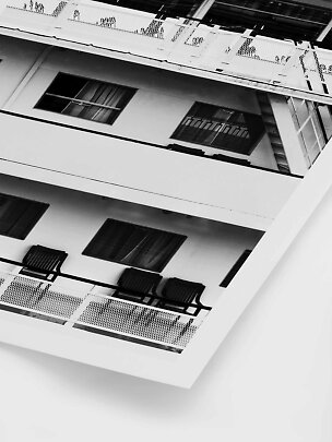 Black-and-white photo of building balconies and windows viewed from below at an angle