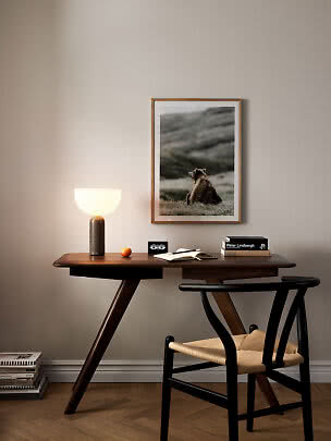Dark wood desk with table lamp, chair, and framed bear poster on the wall