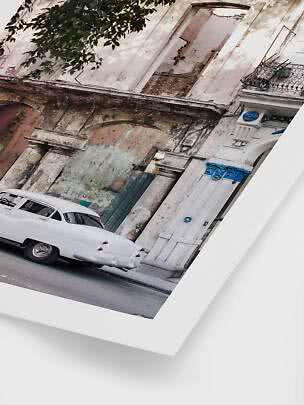 White vintage car parked by a weathered building with columns and blue details