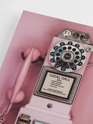 Telefono pubblico retrò rosa con cornetta su sfondo rosa