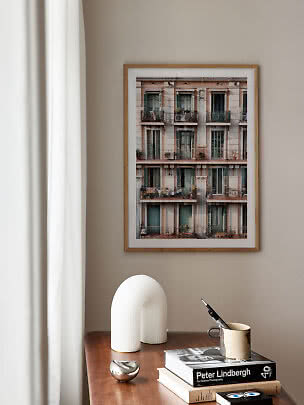 Foto enmarcada de un edificio con balcones sobre una mesa de madera con libros y decoración