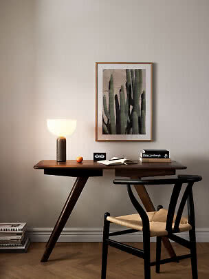 Dunkler Holzschreibtisch mit Tischlampe, Stuhl und gerahmtem Kaktusbild an der Wand