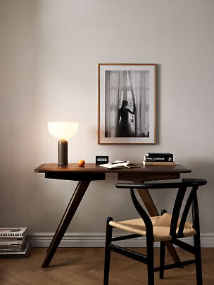 Scrivania in legno scuro con lampada accesa, libro, sedia e foto in bianco e nero incorniciata