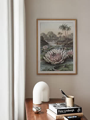 Framed botanical print with water lilies above a wooden table with books and decor