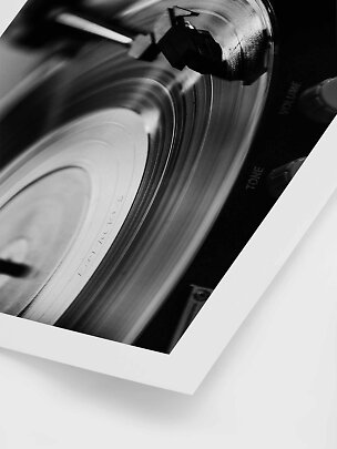 Nærbillede i sort-hvid af en pladespiller med roterende vinyl og pickupnål