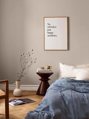 Minimalistisk soveværelse med indrammet citatplakat over sengen og blåt sengetæppe