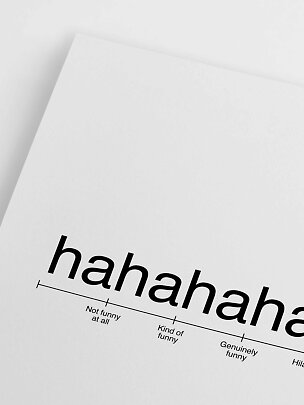 Nærbillede af hvid typografiplakat med ordet "hahahaha" og en humor-skala nederst