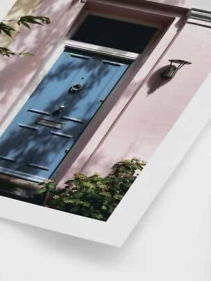 Blue front door in a pink facade with wall light and flowering plants below